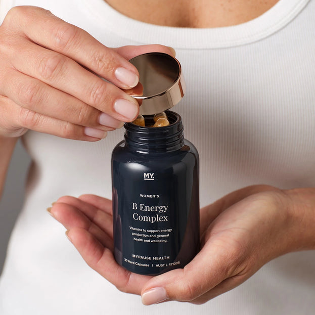 A woman opening a bottle of MyPause Women's B Energy Complex.