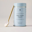 Daily Creatine Support tin with a scoop of powder on a gold spoon.