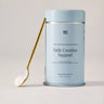 Daily Creatine Support tin with a scoop of powder on a gold spoon.