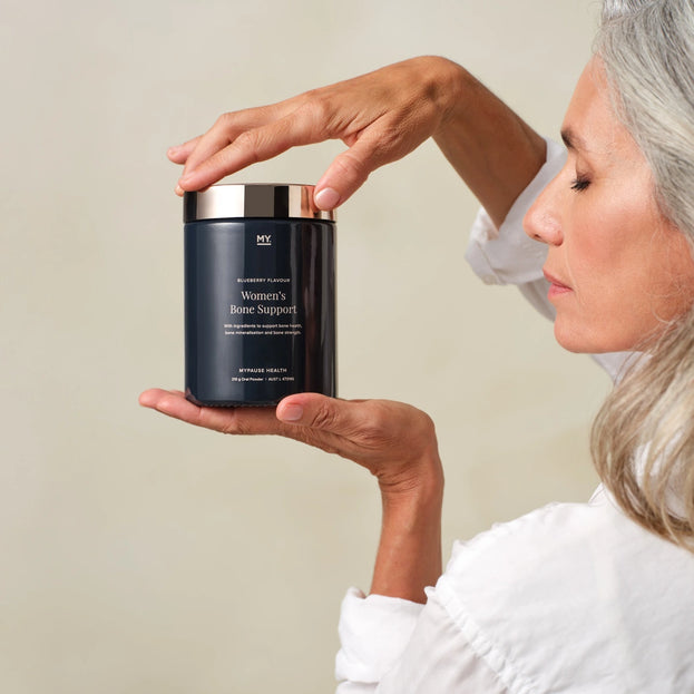 Women's Bone Support 210 g tub held in a woman's hands.