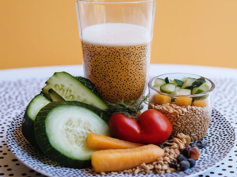 A plate of fresh vegetables and fruit beside a breakfast shake