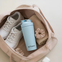 The MyPause steel shaker bottle packed in a cream tote bag with trainers and a scrunchie.