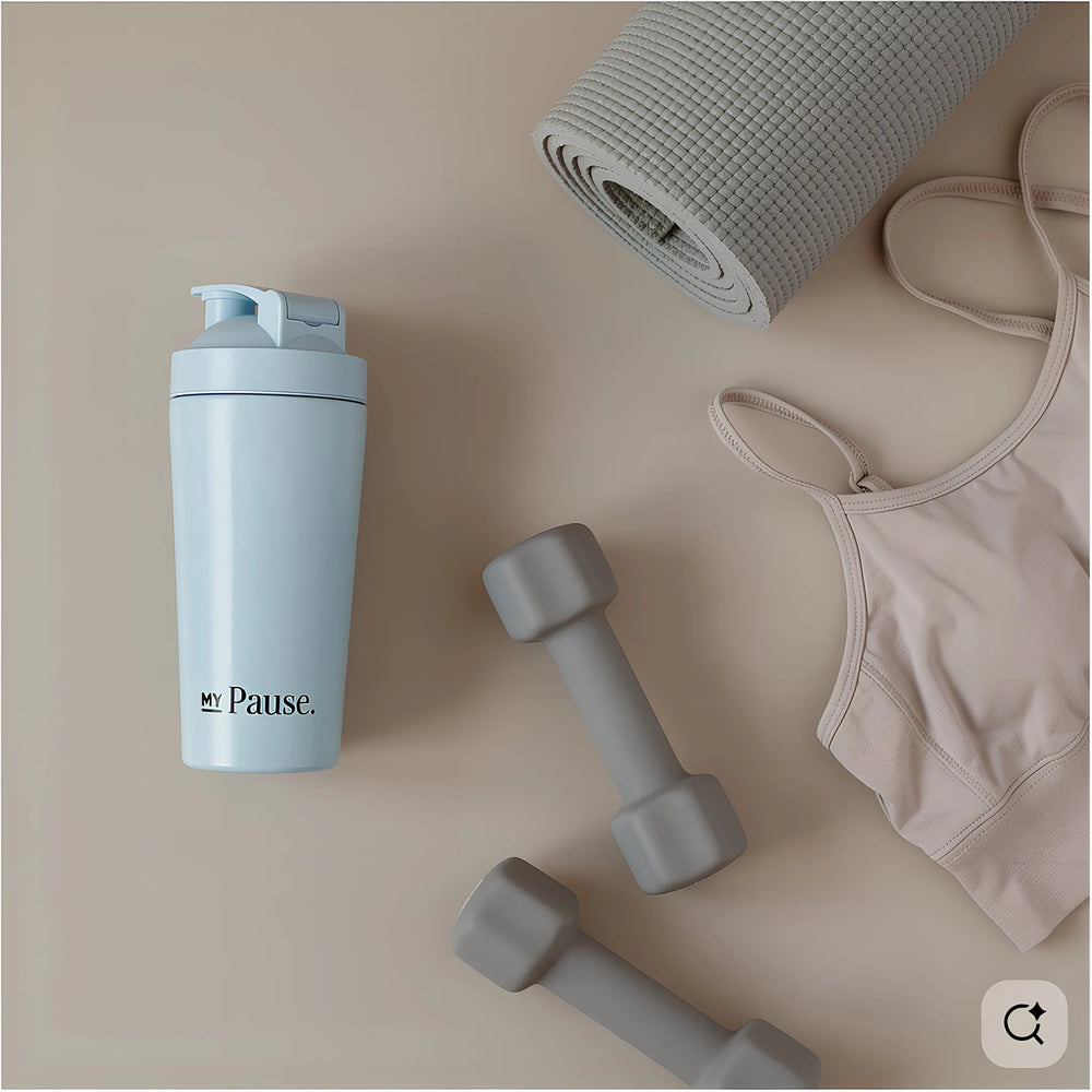 The MyPause steel shaker bottle in a flat lay with dumbbells, a rolled yoga mat and a sports bra.