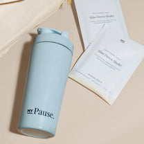 The MyPause steel shaker bottle lying beside MyPause product packaging on cream linen.