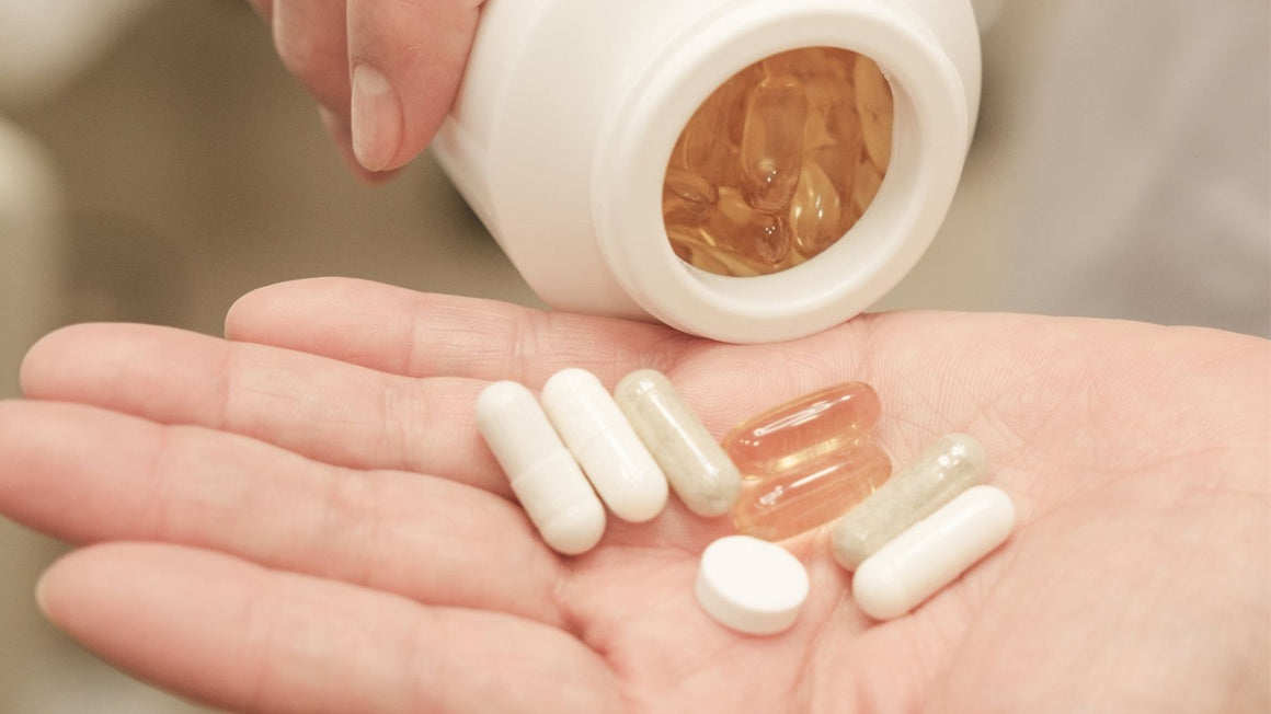 A hand holding supplement capsules next to a medication pack